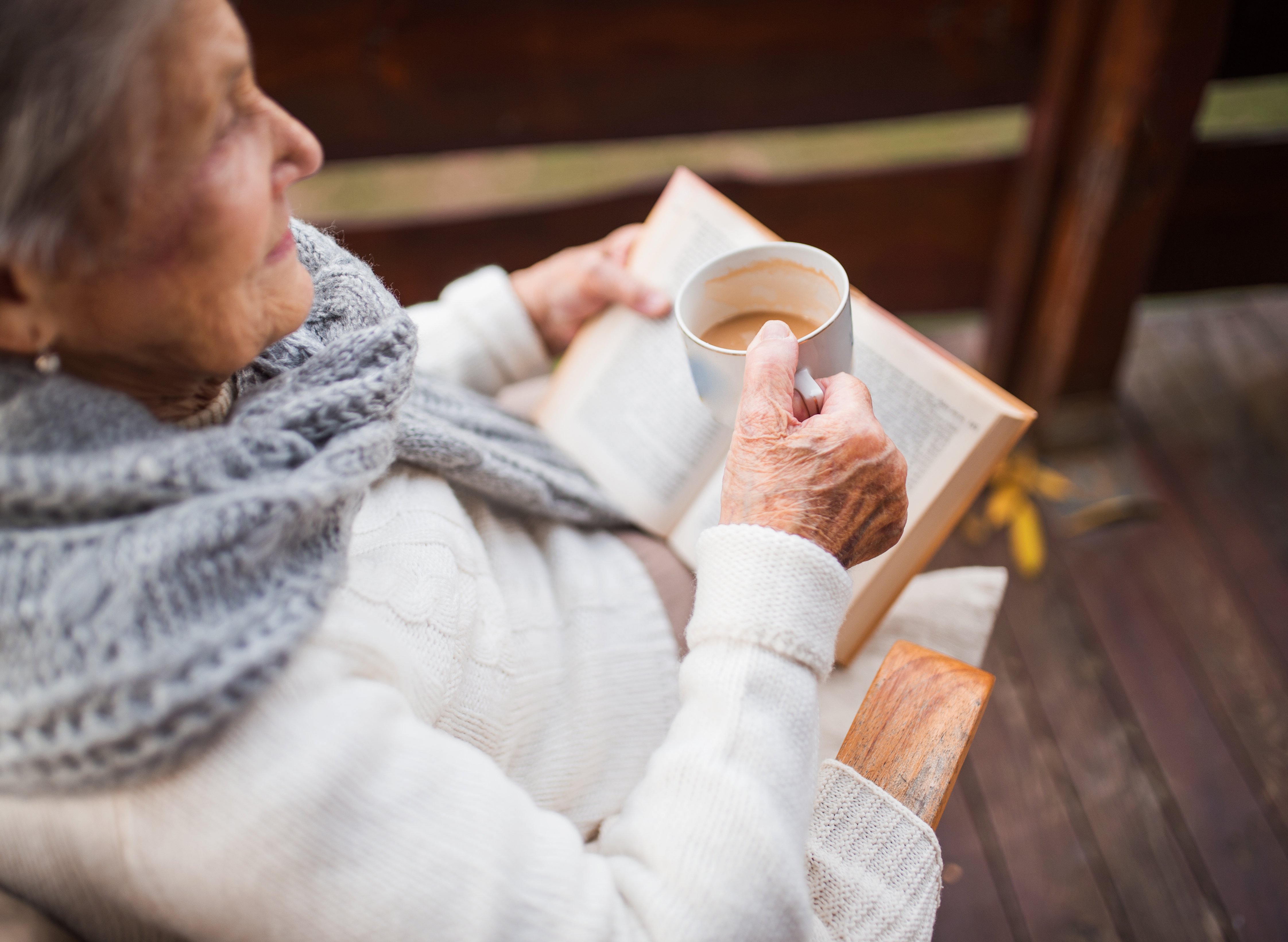 Personne âgée lisant un livre avec un café à la main