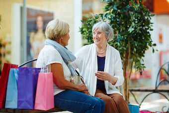 deux femmes personnes agées qui parlent sur un banc de centre commercial