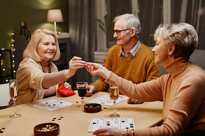 Groupe de trois personnes âgées qui jouent à un jeu sur une table de cuisine