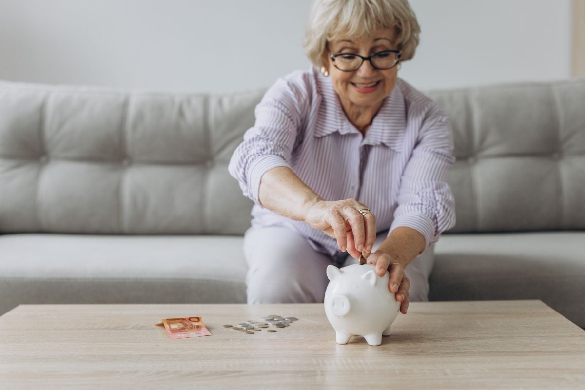 une personne retraitée met ses économies dans une tirelire
